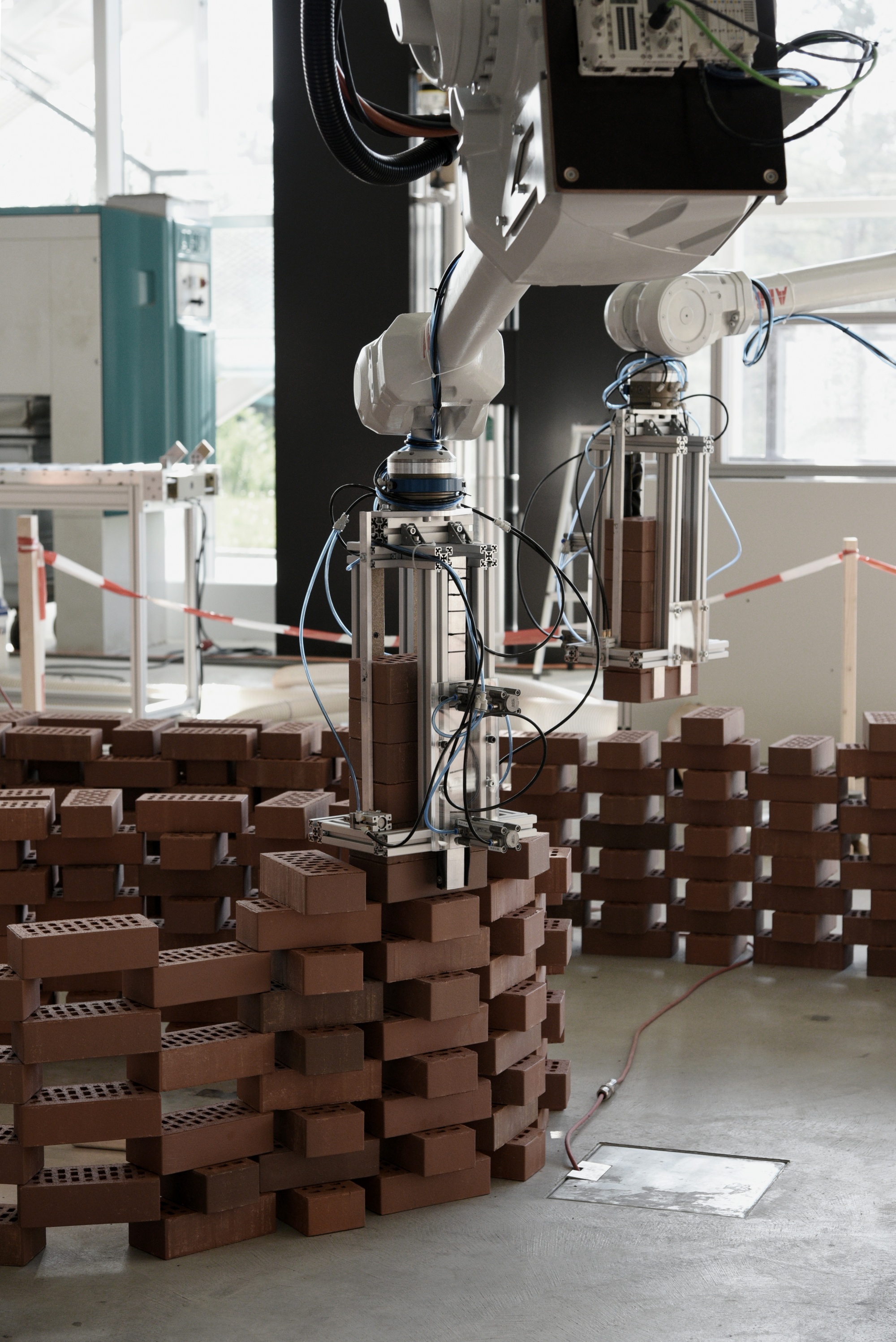 two robotic arms assembling bricks to build the wall, placing the bricks using custom built end effectors